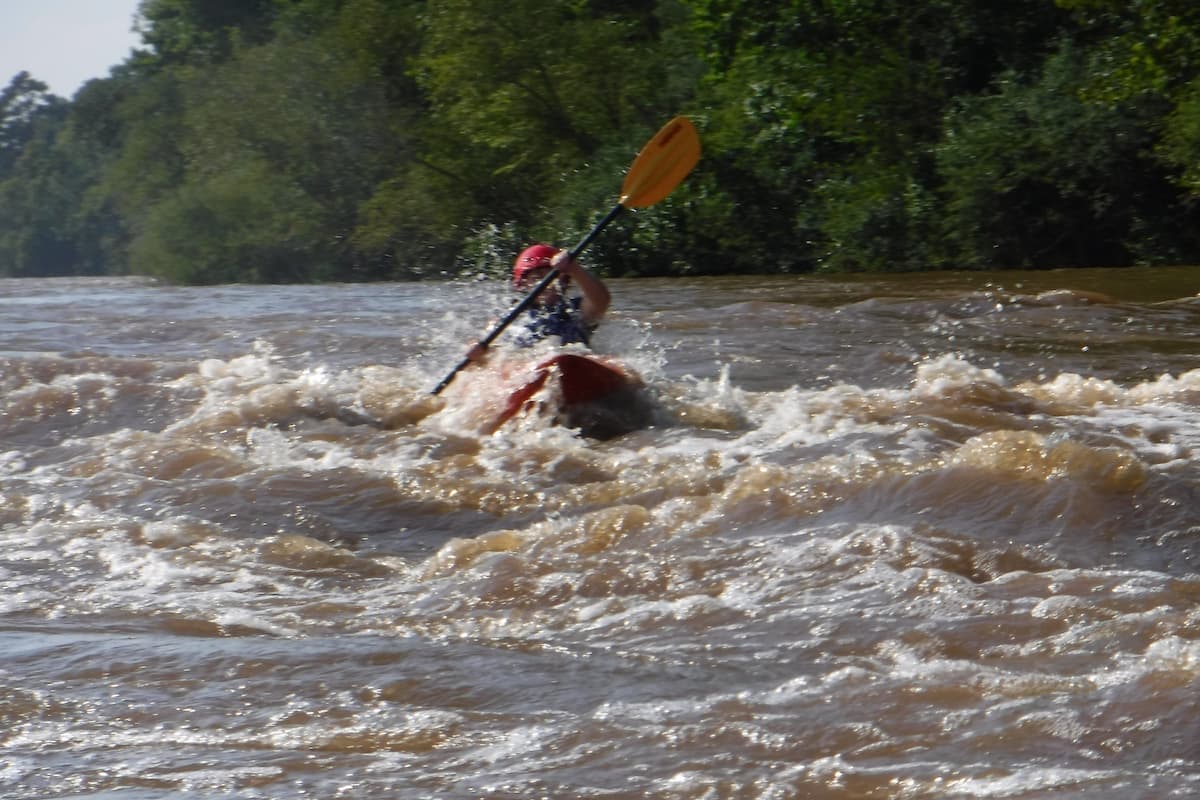 Kayaker paddling through rapids on the Cape Fear River near Lillington, NC