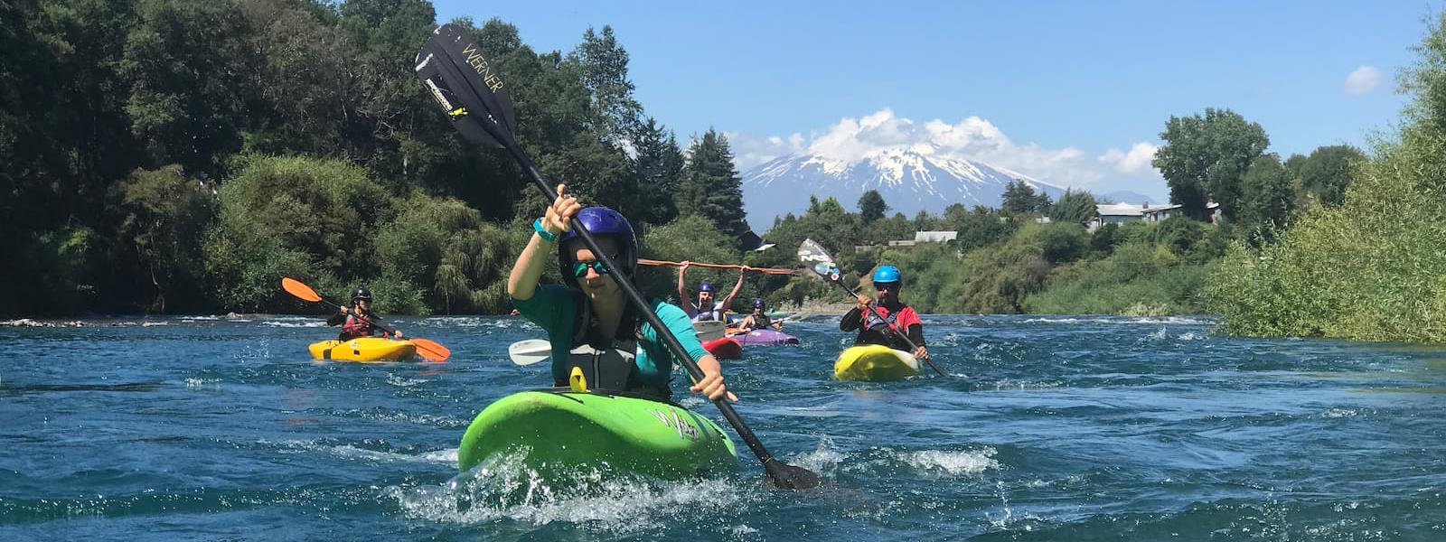 Group of kayakers paddling with volcano in the backgroun in Pucón, Chile