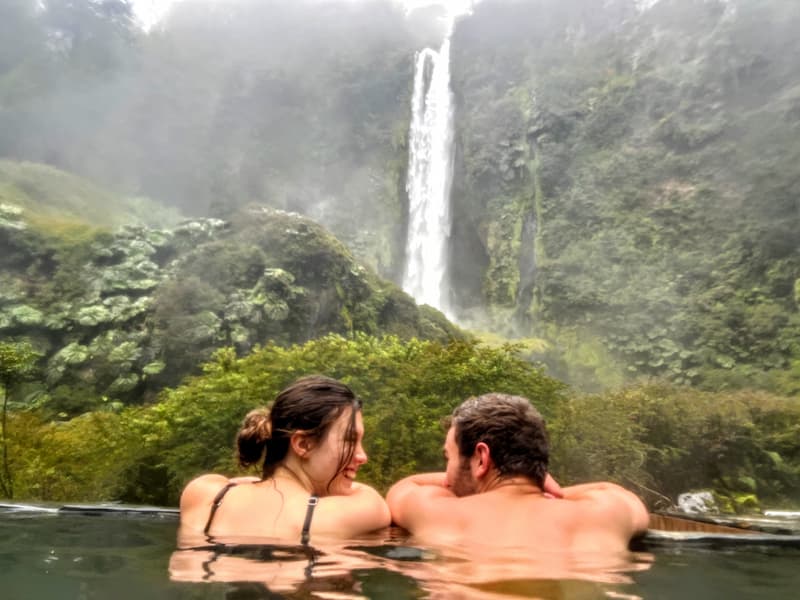 Couple swimming next to beautiful waterfall near Pucón, Chile