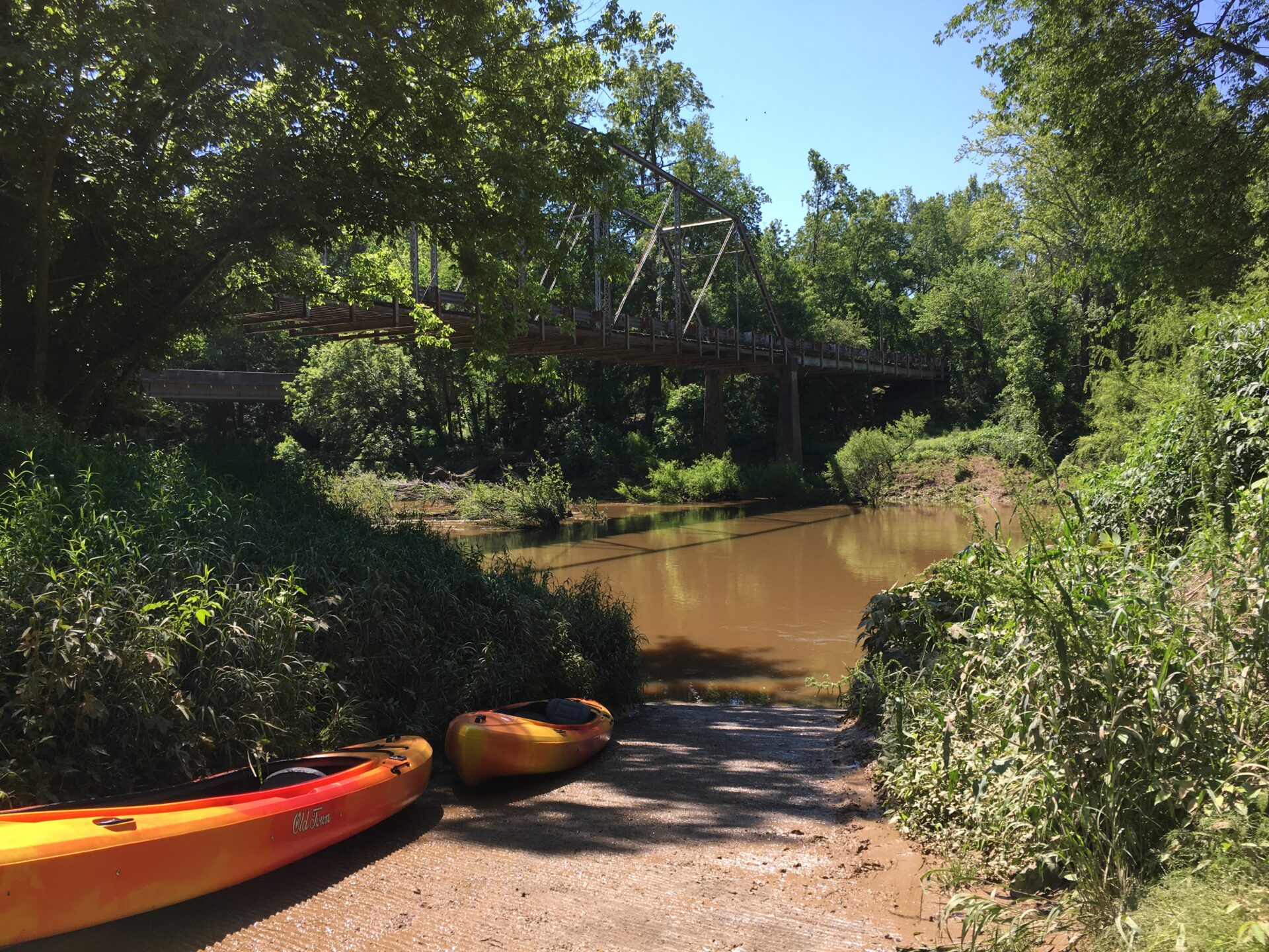 orange and yellow kayaks lined up along a primitive river ramp on Deep River, Sanford NC